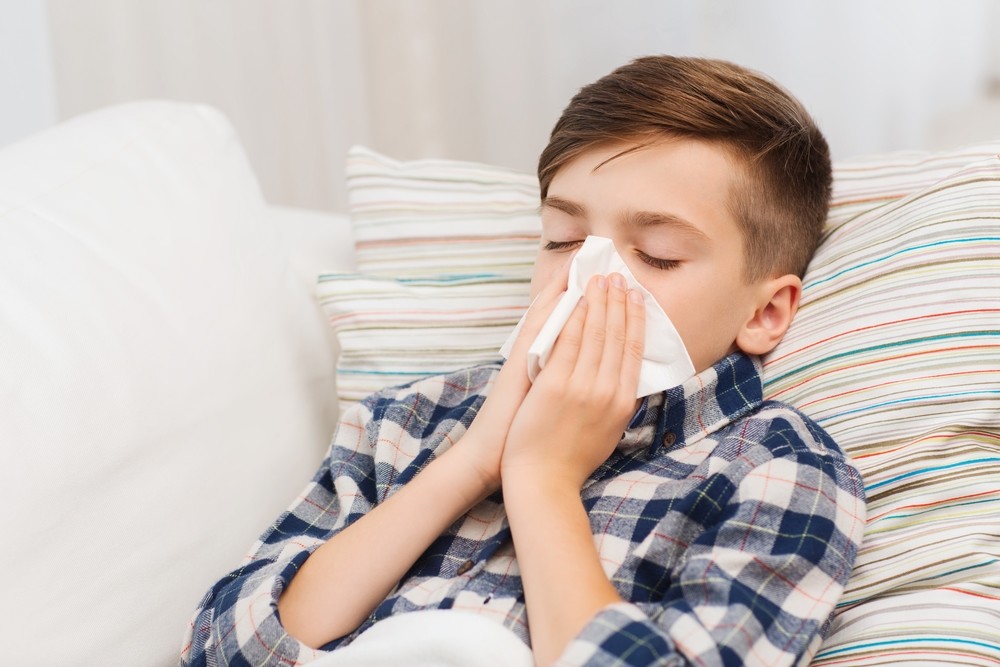 Boy with allergic rhinitis blowing his nose